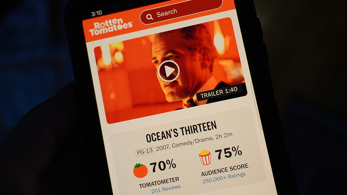 A phone displaying Ocean's Thirteen on Rotten Tomatoes with a 70% score.