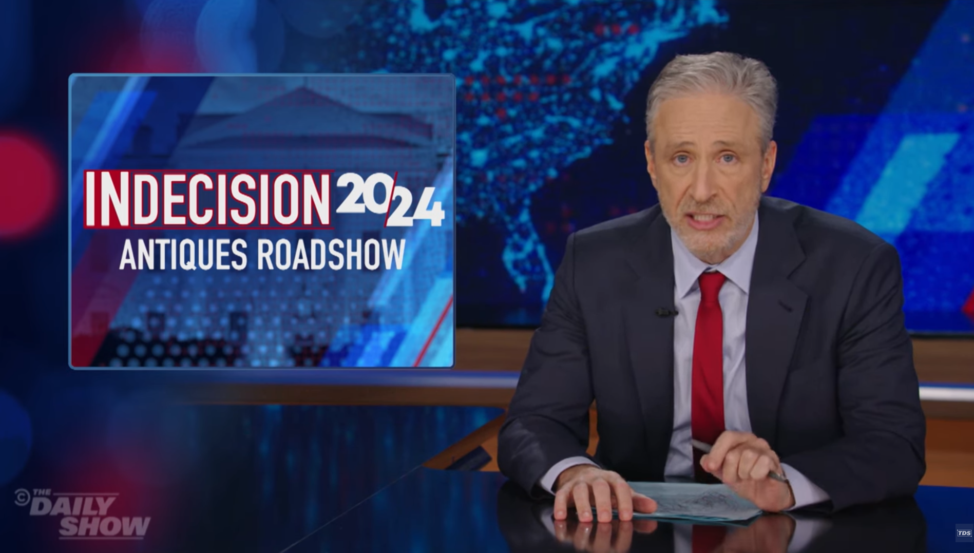 Jon Stewart on The Daily Show next to an Indecision 2024 - Antiques Roadshow graphic.